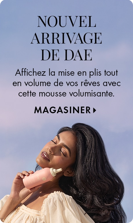 Fond bleu dégradé avec texte « Nouveauté dae » et « Affichez la mise en plis tout en volume de vos rêves avec cette mousse volumisante : Magasiner. » Une personne tient une bouteille de mousse dae rose. Des cheveux longs ornent la moitié inférieure de l’im