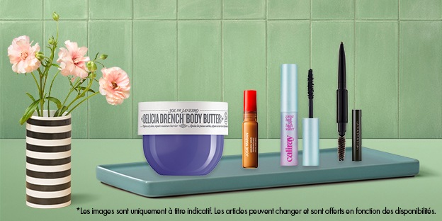  Un vase rayé avec des fleurs roses est posé à gauche à côté d’un plateau présentant divers essentiels beauté, y compris un pot de beurre pour le corps violet et plusieurs articles de maquillage, sur un fond carrelé vert.