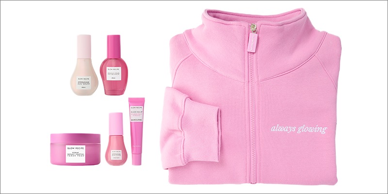 Assortiment de soins pour la peau Glow Recipe, comprenant la lotion tonique, le sérum, l’hydratant et le soin pour les lèvres présentés dans un emballage rose emblématique à côté d’un chandail rose « Always Glowing » à capuchon avec fermeture éclair sur un