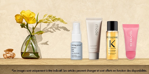 Shampoing sec Perfect hair Day de Living Proof, sérum liquide éclat aux peptides de rhode, huile pour les cheveux Elixir Ultime de Kérastase et brillant à lèvres en gelée ShineOn de Tower 28 présentés sur une tablette à côté d’un petit vase avec des fleurs