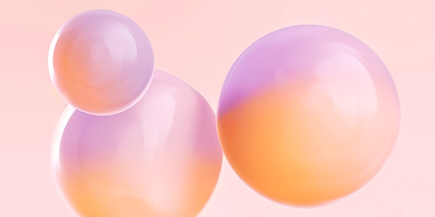 Three translucent, glossy spheres with pastel gradients of pink, purple, and orange on a soft pink background. No text or identifiable objects.