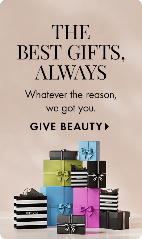 Neutral beige background with text reading “The Best Gifts, Always” and “Whatever the reason, we got you,” followed by “Give Beauty.” A stack of colorful gift boxes and Sephora‑striped shopping bags with ribbon bows sits at the bottom.