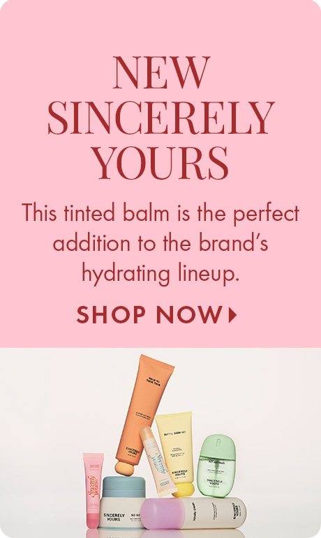 Soft pink background with text reading “New Sincerely Yours” and “This tinted balm is the perfect addition to the brand’s hydrating lineup,” followed by “Shop Now.” A group of colorful Sincerely Yours skincare and balm products is arranged at the bottom.