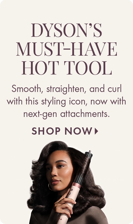 Light beige background with text reading “Dyson’s Must‑Have Hot Tool” and “Smooth, straighten, and curl with this styling icon, now with next‑gen attachments,” plus “Shop Now.” A Dyson styling tool is shown beside a person holding it.