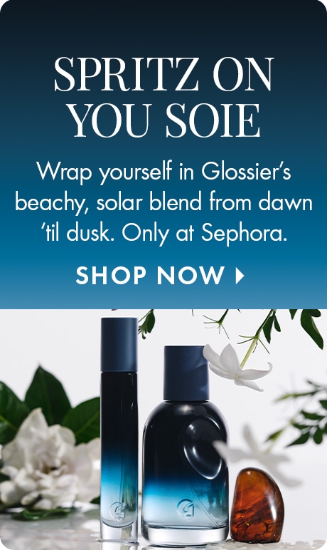Blue gradient background with text reading “Spritz On You Soie.” Below: “Wrap yourself in Glossier’s beachy, solar blend from dawn ’til dusk. Only at Sephora,” and “Shop Now.” Two dark blue Soie fragrance bottles sit among white flowers.