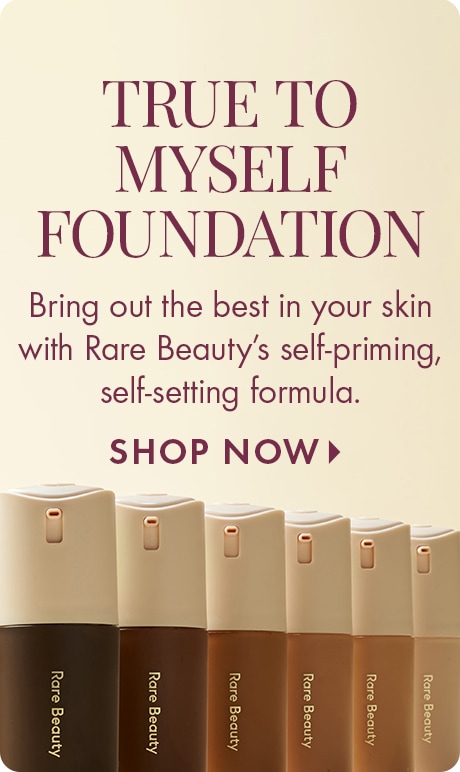 Cream background with text reading “True to Myself Foundation.” Below: “Bring out the best in your skin with Rare Beauty’s self‑priming, self‑setting formula,” and “Shop Now.” A row of Rare Beauty foundation bottles in multiple shades lines the bottom.