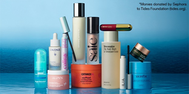 A lineup of skincare, hair, and makeup products arranged on a blue surface against a water‑inspired background. A small note in the corner reads that monies are donated by Sephora to the Tides Foundation.
