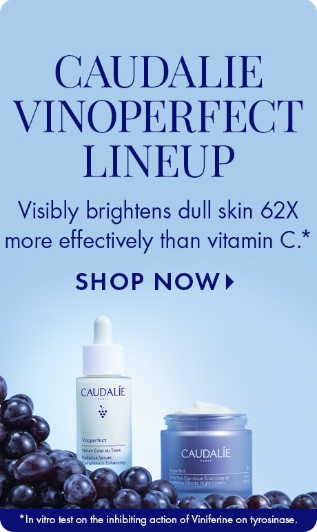 Light blue background with text reading “Caudalie Vinoperfect Lineup.” Below: “Visibly brightens dull skin 62X more effectively than vitamin C,” with “Shop Now.” A Vinoperfect serum bottle and cream jar sit among dark grapes.