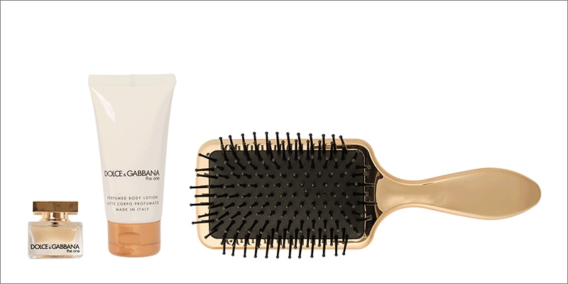 Dolce & Gabbana items including a perfume bottle, body lotion tube, and gold paddle hair brush.