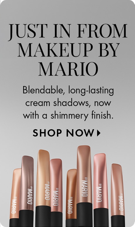 "JUST IN FROM MAKEUP BY MARIO" "Blendable, long-lasting cream shadows, now with a shimmery finish." "SHOP NOW" Promotional beauty ad featuring multiple Makeup by Mario cream shadow sticks in metallic nude and rose tones lined up along the bottom.