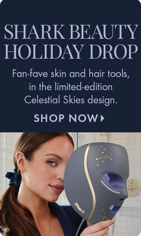 "SHARK BEAUTY HOLIDAY DROP." Text: "Fan-fave skin and hair tools, in the limited-edition Celestial Skies design." "SHOP NOW." Dark blue background above a person holding a gray Shark Beauty mask with gold accents and constellation designs.