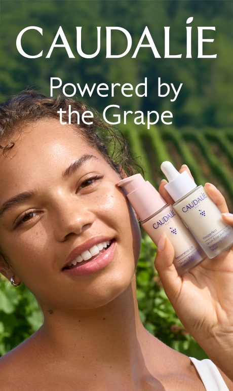Caudalie. Powered by the grape. Image of model holding product bottle.