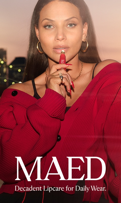 maed. decadent lipcare for daily wear. image of model holding product.