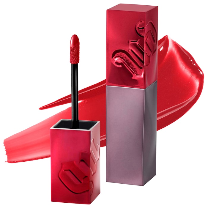 An open tube of red liquid lipstick with a swatch behind it